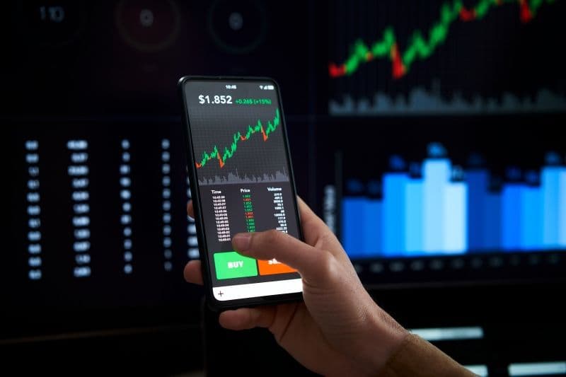 persona sostiene un celular con inversiones.jpg